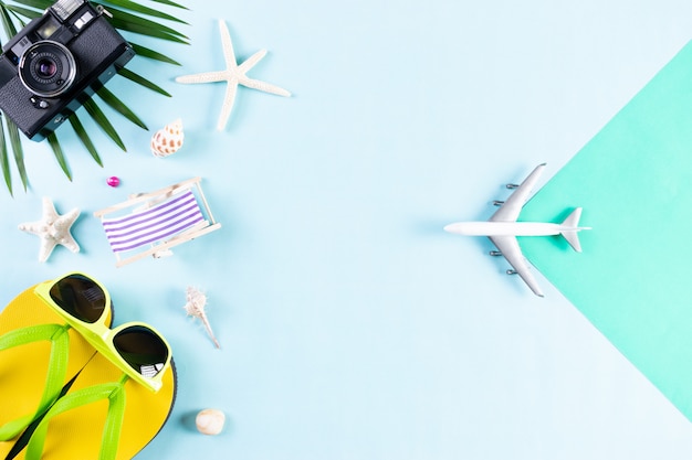 Zdjęcie lato, akcesoria plażowe, aparat fotograficzny, samolot, okulary przeciwsłoneczne, rozgwiazda flip flop na niebieskim tle pastelowym.