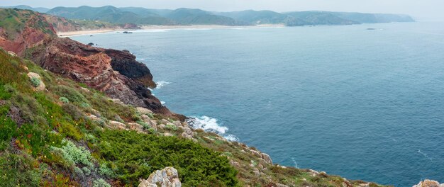 Lato skaliste wybrzeże Atlantyku mglisty widok z piaszczystej plaży (Costa Vicentina, Algarve, Portugalia).