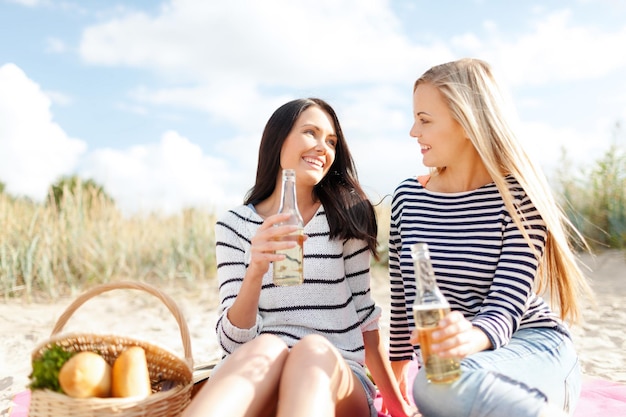 lato, wakacje, wakacje, koncepcja szczęśliwych ludzi - uśmiechnięte dziewczyny z butelkami piwa lub napojami bezalkoholowymi na plaży