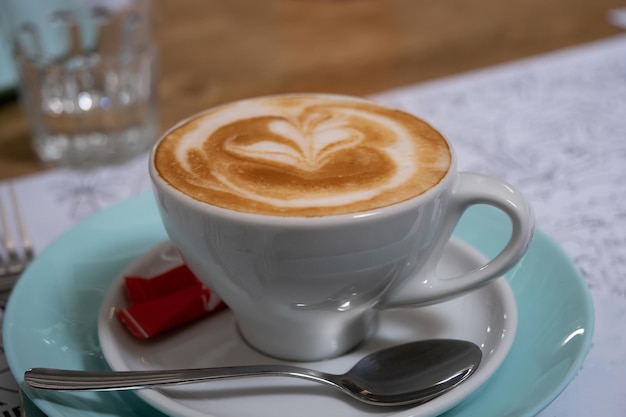 Latte art w filiżance cappuccino przy stoliku kawowym