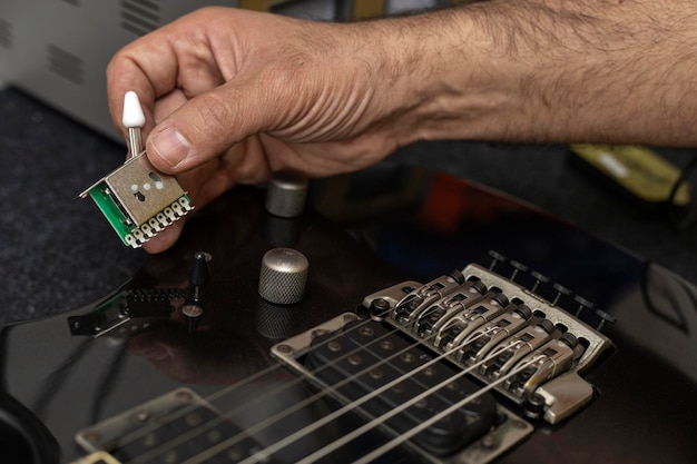 Latynoamerykański lutnik trzyma w dłoni nowy przełącznik gitary elektrycznej, który się zmieni