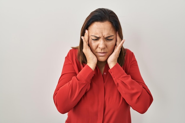 Latynoska dojrzała kobieta stojąca nad białym tłem z ręką na głowie z powodu bólu głowy z powodu stresu. cierpiący na migrenę.