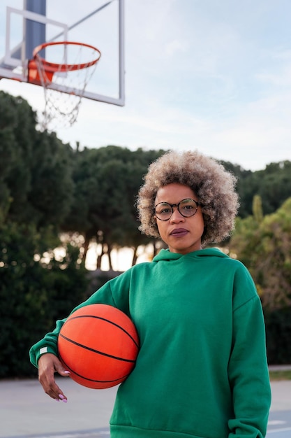 Latynoska kobieta na zewnątrz z piłką do koszykówki pod pachą koncepcja miejskiego sportu na ulicy kopiuje miejsce na tekst