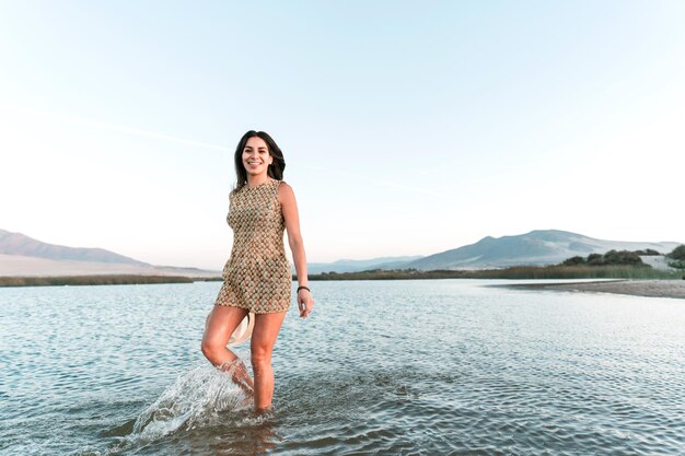 Latynoska kobieta spacerująca w wodzie uśmiechnięta z aparatami ortodontycznymi szczęśliwa