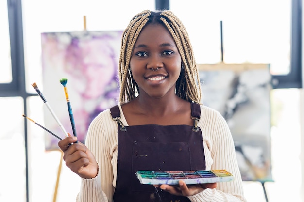 Latynoska latynoska kobieta maluje na płótnie farbami olejnymi w warsztacie
