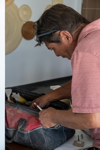 Latynoski mężczyzna szukający narzędzi w swojej skrzynce na narzędzia Hiszpan ze śrubokrętem w ręku