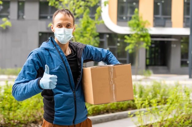 Latynoski Młody Dostawca Noszący Maskę Podczas Noszenia Paczki Podczas Epidemii Koronawirusa.