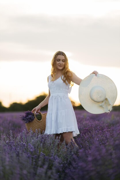Lawendowe pole portret seksownej dziewczyny w słomkowym kapeluszu Prowansja Francja Dziewczyna w białej sukni spacerująca po lawendowych polach o zachodzie słońca