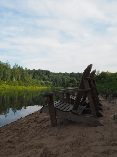 Ławka nad wodą jest otoczona drzewami, a niebo jest błękitne.