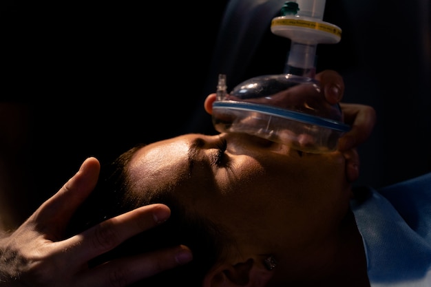 Leczenie ciężkiej postaci koronowirusa covid-19. Lekarz zakłada maskę do sztucznej wentylacji płuc na oddziale intensywnej terapii