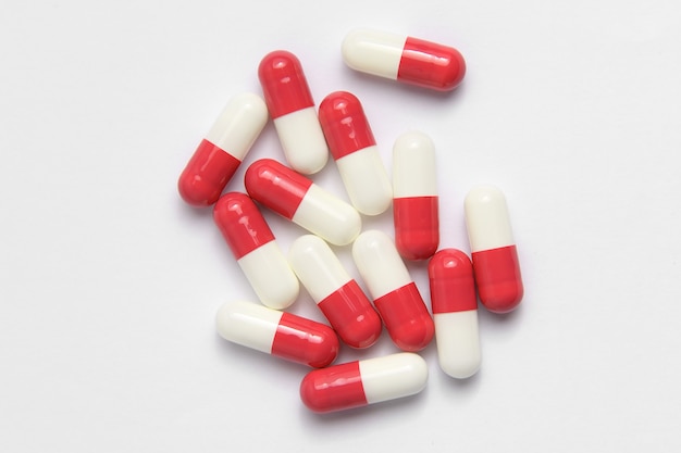 Lek w cylindrycznych kapsułkach w kolorze czerwonym na białym tle