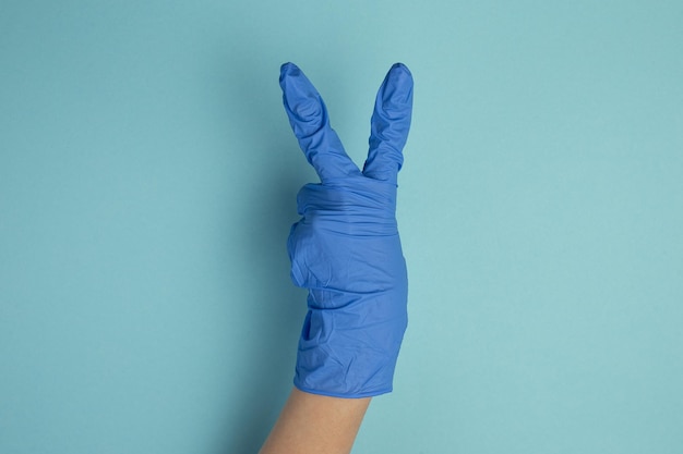 Zdjęcie lekarka w niebieskich rękawiczkach styrylowych i pokazująca różne gesty rąk na niebieskim tle koncepcja zdrowia szpitalna opieka medyczna