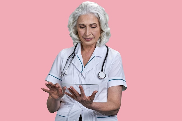 Lekarka ze stetoskopem przy użyciu futurystycznego przezroczystego tabletu pc starsza kobieta lekarz pracuje nad