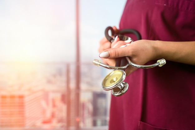 Lekarka ze stetoskopem w dłoniach w ubraniach stoi w prestiżowym szpitalu