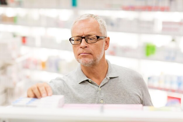 Lekarstwo farmaceutyczne opieka zdrowotna i koncepcja ludzi starszy mężczyzna klient z lekiem w aptece