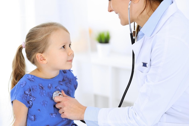 Lekarz bada małą dziewczynkę stetoskopem. Szczęśliwy uśmiechający się pacjent dziecko w zwykłym badaniu lekarskim. Koncepcje medycyny i opieki zdrowotnej.