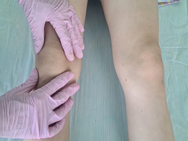 Zdjęcie lekarz bada małego pacjenta z problemami z kolanem w klinice