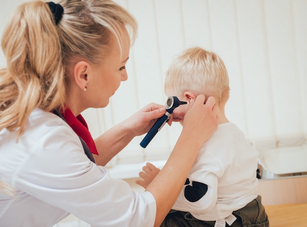 Zdjęcie lekarz bada ucho za pomocą otoskopu w pokoju pediatry.