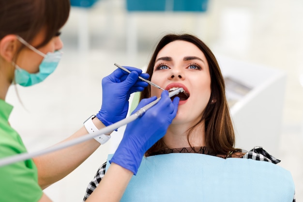 Lekarz dentysta wierci zęby młodą kobietą. Dziewczyna u dentysty