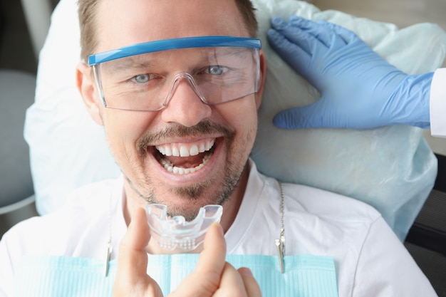 Lekarz Dentysta Zakładający Plastikową Osłonę Nocną Mężczyźnie W Gabinecie Stomatologicznym