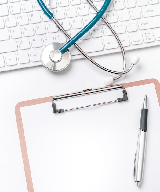 Zdjęcie lekarz diagnozuje koncepcję stetoskopu na klawiaturze komputera z etui na dokumentację medyczną i długopisem na białym stole roboczym widok z góry płaska kopia miejsca