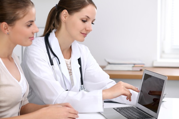 Lekarz i pacjent siedzący przy biurku Lekarz wskazujący na laptopa Pojęcie medycyny i opieki zdrowotnej