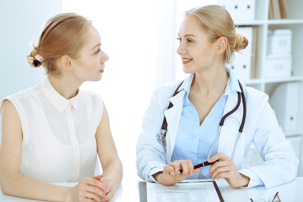 Lekarz i pacjent siedzi przy biurku. Lekarz lub terapeuta stawia diagnozę. Koncepcja opieki zdrowotnej, medycyny i obsługi pacjenta.
