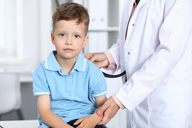 Lekarz i pacjent w szpitalu Szczęśliwy mały chłopiec bawi się podczas badania stetoskopem Koncepcja opieki zdrowotnej i ubezpieczenia