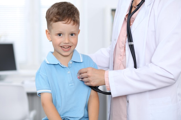 Lekarz i pacjent w szpitalu Szczęśliwy mały chłopiec bawi się podczas badania stetoskopem Koncepcja opieki zdrowotnej i ubezpieczenia