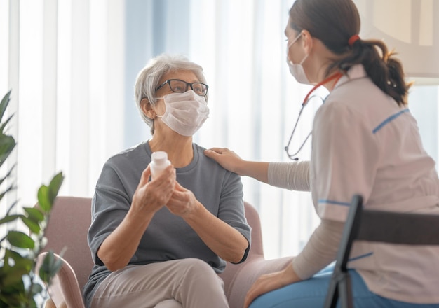 Lekarz i starsza kobieta nosząca maseczki na twarz podczas epidemii koronawirusa i grypy. Wirus ochrona. COVID-2019. Zakładanie masek.