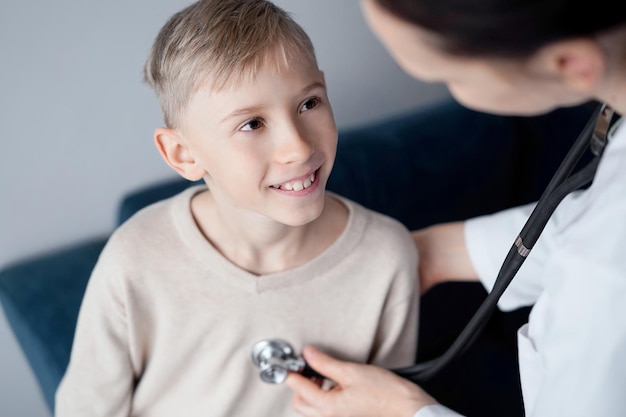 Lekarz i szczęśliwy uśmiechnięty chłopiec pacjent podczas domowej kontroli lekarskiej. Medycyna, koncepcje opieki zdrowotnej.