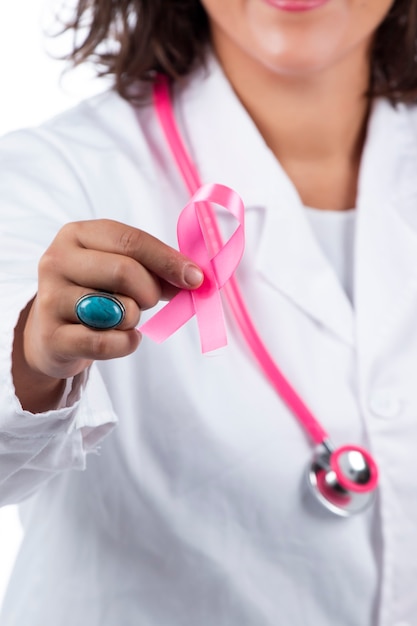 lekarz kobieta z różowym stetoskopem trzymając raka piersi różową wstążką na białym tle.