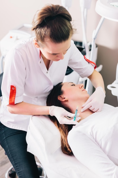 Lekarz medycyny estetycznej pracuje z młodą pacjentką w salonie kosmetycznym