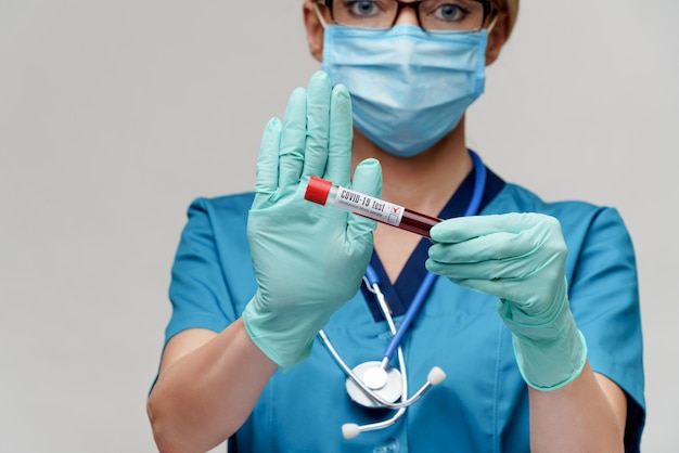 Lekarz medycyny pielęgniarki kobieta jest ubranym maskę ochronną i rękawiczki - trzymający wirusową badanie krwi tubki