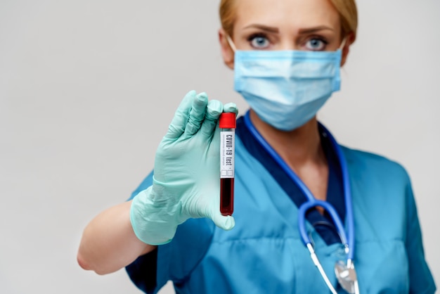 Lekarz medycyny pielęgniarki kobieta jest ubranym maskę ochronną i rękawiczki - trzymający wirusowego badanie krwi