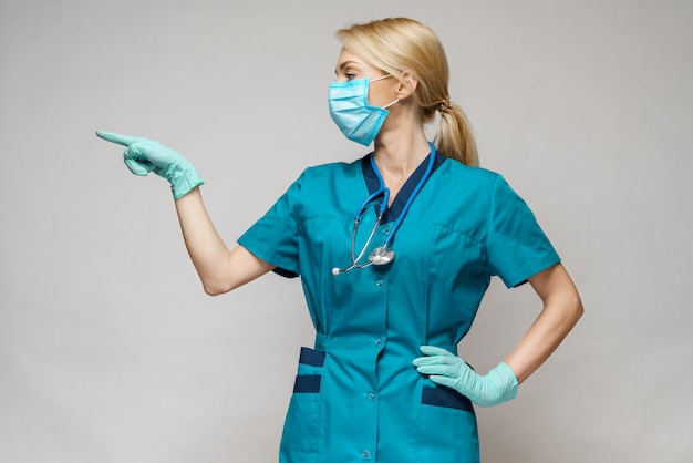 Zdjęcie lekarz medycyny pielęgniarki kobieta nosi maskę ochronną i rękawice lateksowe - pokazując na wirtualnej liście