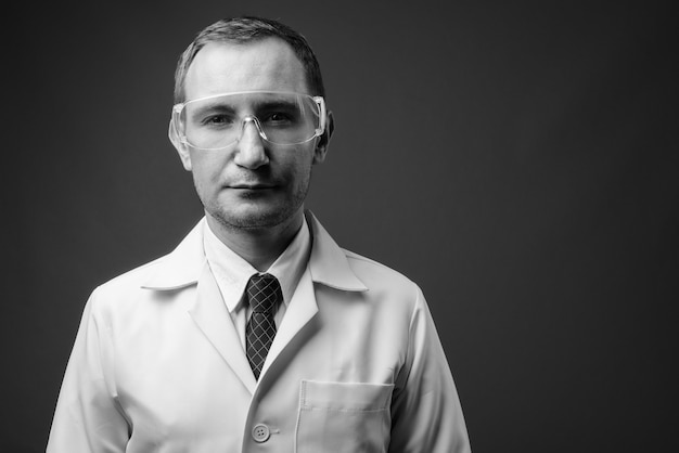 Zdjęcie lekarz mężczyzna jako naukowiec w okularach ochronnych szarej ścianie w czerni i bieli