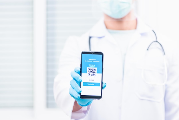 Lekarz mężczyzna w medycznej masce pokazuje aplikację smartfon mobilny cyfrowy paszport szczepionkowy koronawirus COVID-19 certyfikat potwierdzający koncepcję pasza zdrowotnego szczepienia