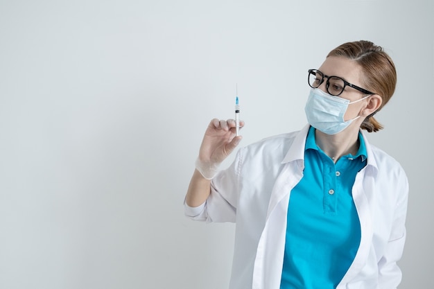 Lekarz na jasnej powierzchni trzyma strzykawkę ze szczepionką na koronawirusa