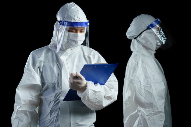 Lekarz noszący środki ochrony indywidualnej i osłonę twarzy, trzymając w rękach raport laboratoryjny z wirusa korony / covid-19