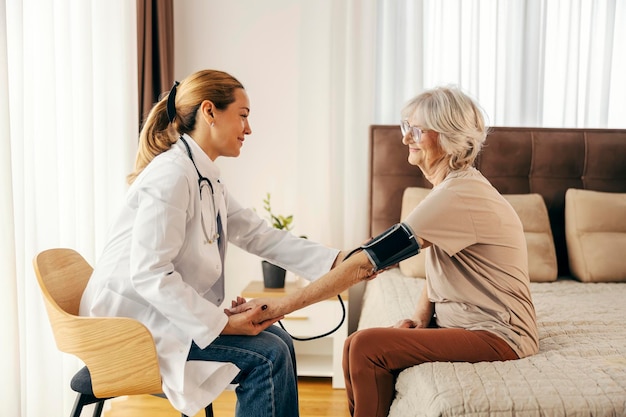 Lekarz odwiedza starszą kobietę w domu i mierzy jej ciśnienie krwi
