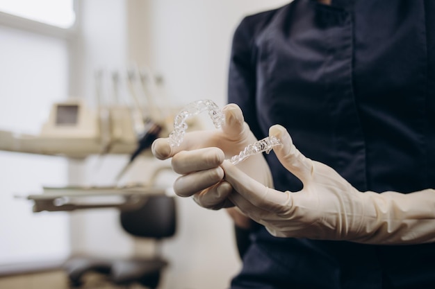 Zdjęcie lekarz ortodonta w rękawiczkach zakładający silikonowe niewidoczne przezroczyste szelki na zęby kobiety w klinice dentystycznej zbliżenie ust widok korekcji leczenia zębów i leczenia w stomatologii