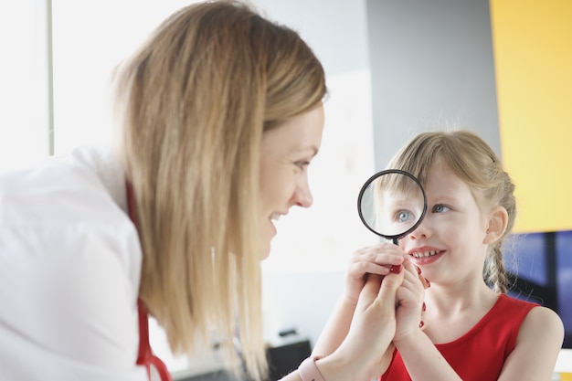 Lekarz Pediatra Z Małą Dziewczynką Trzymającą Szkło Powiększające W Poszukiwaniu Odpowiedniego Leczenia Dla Dziecka