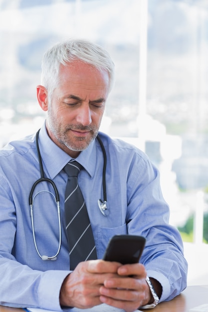 Lekarz pisania wiadomości tekstowej na swoim smartfonie