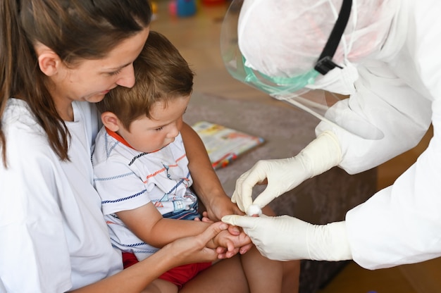Lekarz pobiera od dziecka badanie krwi w domu
