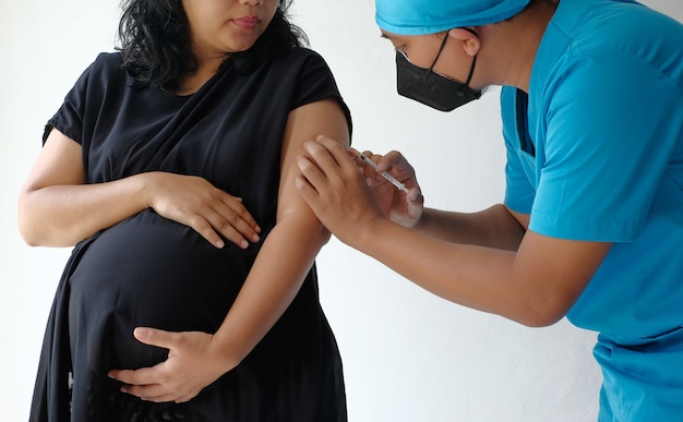 Lekarz podaje szczepionkę kobiecie w ciąży