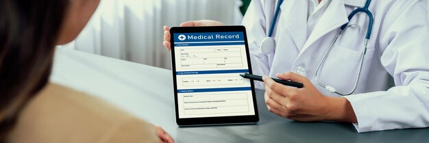 Lekarz pokazuje raport z diagnozy medycznej na tablecie i zapewnia pełne współczucia konsultacje w zakresie opieki zdrowotnej, jednocześnie wspierając i trzymając za rękę młodego pacjenta w gabinecie lekarskim Neoteric