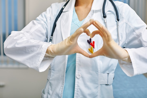 Lekarz pokazuje simbols serca przez ręce złożone w kształcie serca z koncepcją opieki medycznej, Medycyna w szpitalu, kardiologia.