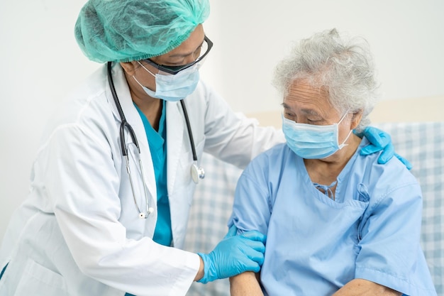 Lekarz pomaga azjatyckiej starszej lub starszej pacjentce starszej kobiety noszącej maskę w szpitalu w celu ochrony infekcji bezpieczeństwa i zabicia Covid19 Coronavirus