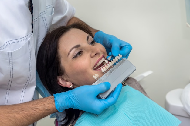 Lekarz porównuje zęby kobiety z próbnikiem w stomatologii